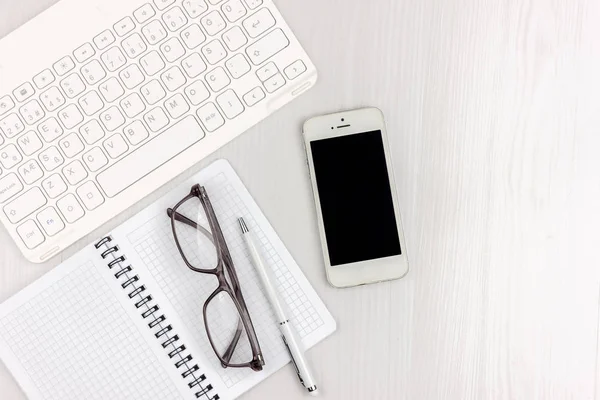 Dizüstü bilgisayar, akıllı telefon, gözlük, dizüstü bilgisayar ve kopya alanı arka plan ile kalem ile beyaz ofis masası düz yatıyordu. Mockup