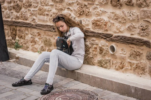 Jong tiener meisje rummaging in een rugzak zitten op de trappen van de oude huis — Stockfoto