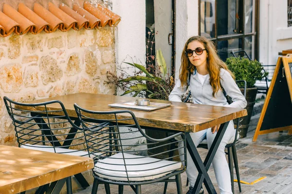 Young beautiful girl sitting in a street cafe in old city of Antalya