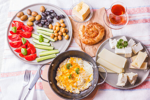 Traditional Turkish breakfast - fried eggs, fresh vegetables, olives, cheese, cake and tea