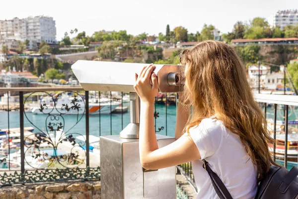 Young girl with long hair looking to the sea by binoculars