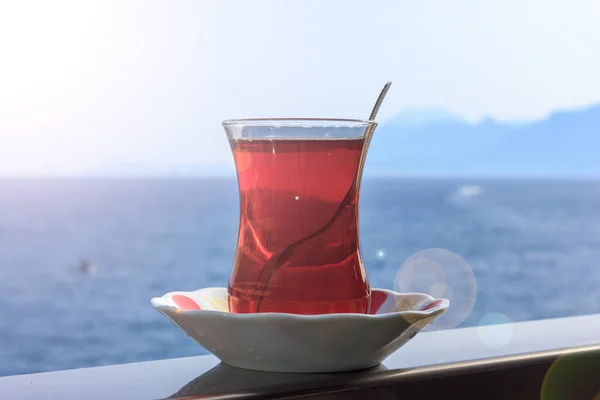Turkish black tea in traditional glass on background of blue Mediterranean sea — Stock Photo, Image