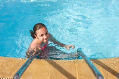 Young teen girl swims and have fun in the outdoor pool