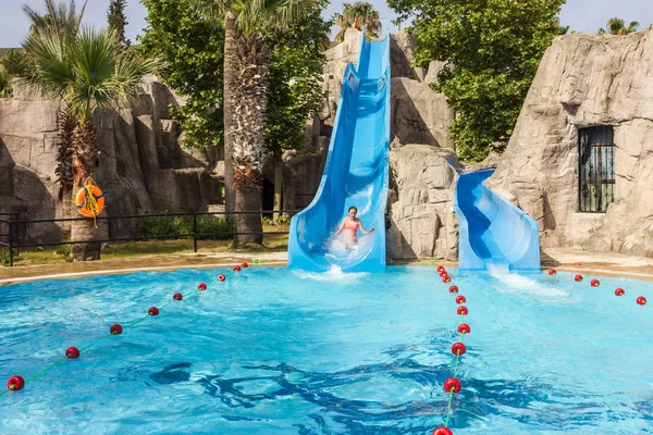 Alegre riendo adolescente chica va abajo por tobogán de agua en el hotel aquapark — Foto de Stock