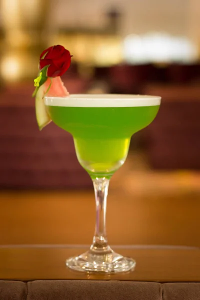 Green alcoholic cocktail with mint in a margarita glass on a bar counter