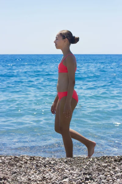 Pretty ung flicka i bikini stående på stranden i närheten av havet — Stockfoto