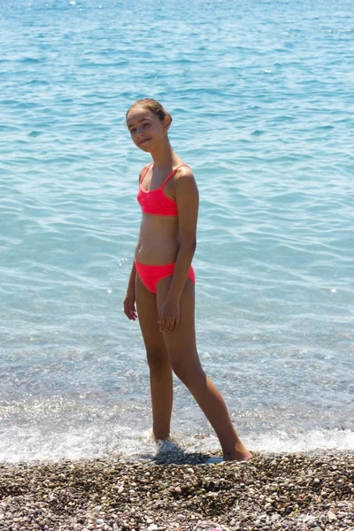 Pretty ung flicka i bikini stående på stranden i närheten av havet — Stockfoto