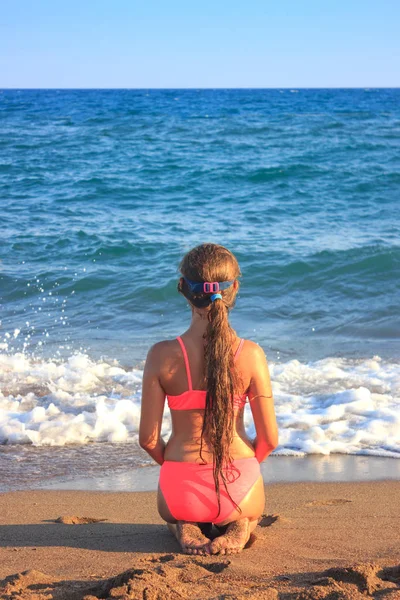 Jovem adolescente sentada na praia olhando para o mar — Fotografia de Stock