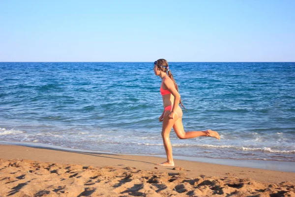 Ung tonåring flicka körs på stranden längs havet — Stockfoto