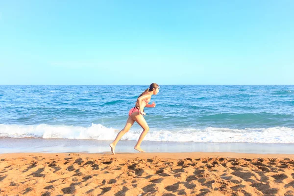 Jovem menina adolescente corre na praia ao longo do mar — Fotografia de Stock