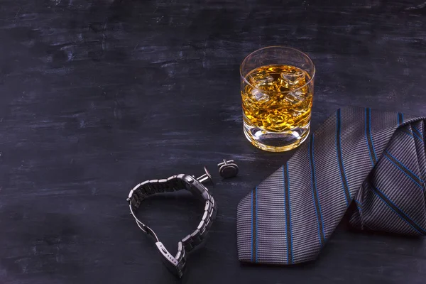 Concepto masculino para el día del padre. Corbata, relojes, gemelos y un vaso de whisky con hielo — Foto de Stock