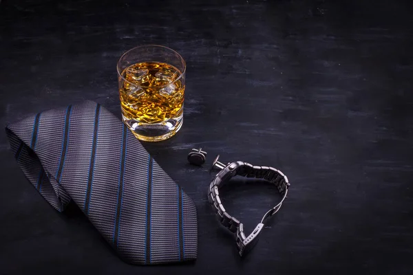 Concepto masculino para el día del padre. Corbata, relojes, gemelos y un vaso de whisky con hielo — Foto de Stock