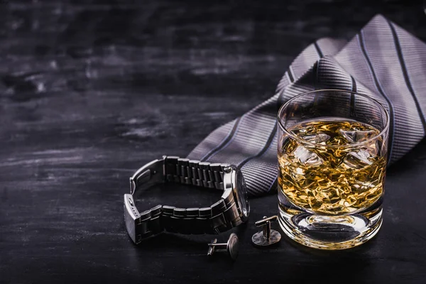 Concepto masculino para el día del padre. Corbata, relojes, gemelos y un vaso de whisky con hielo — Foto de Stock