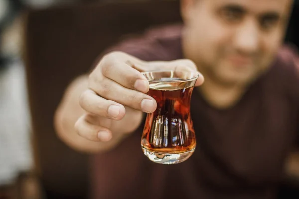 Hombre turco sostiene el té turco negro en un vaso tradicional — Foto de Stock