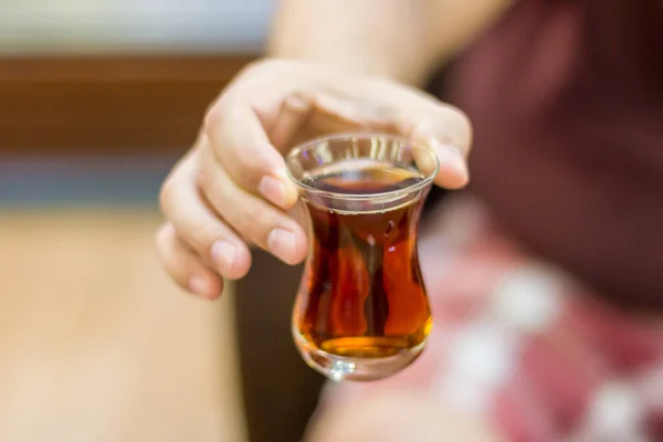 Turkisk man håller ut svart turkiskt te i ett traditionellt glas — Stockfoto
