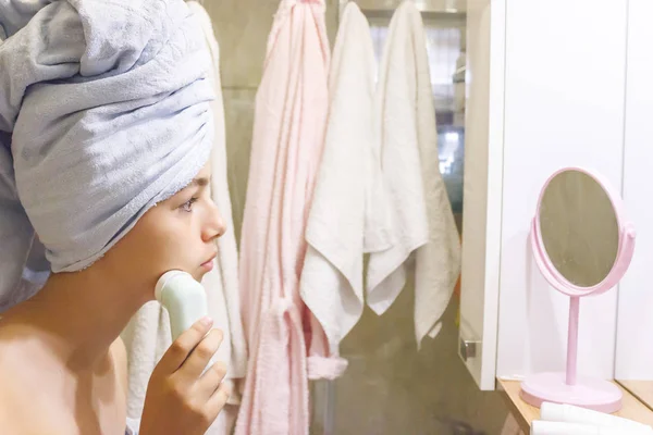Joven hermosa adolescente chica en una toalla haciendo masaje facial por sí misma — Foto de Stock