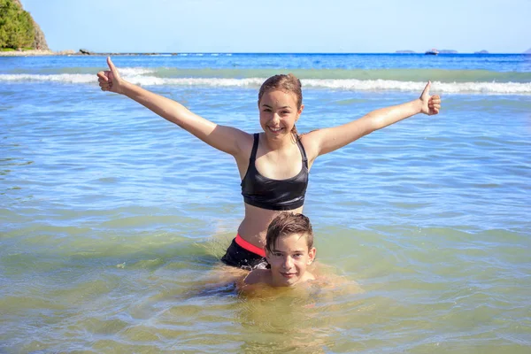 Jóvenes y felices adolescentes niño y niña jugando en el mar —  Fotos de Stock