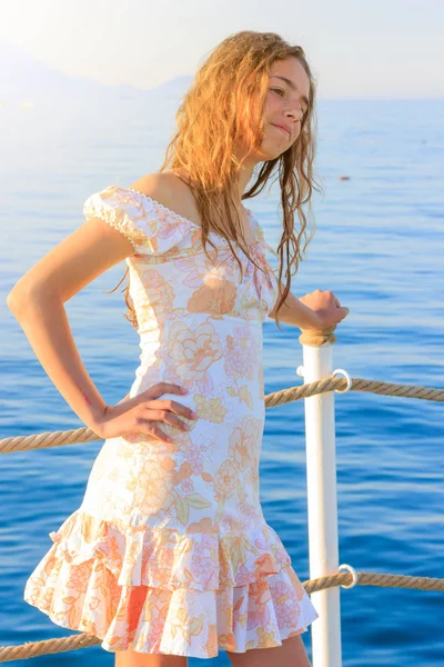 Linda chica adolescente en vestido y con el pelo largo en el muelle junto al mar —  Fotos de Stock