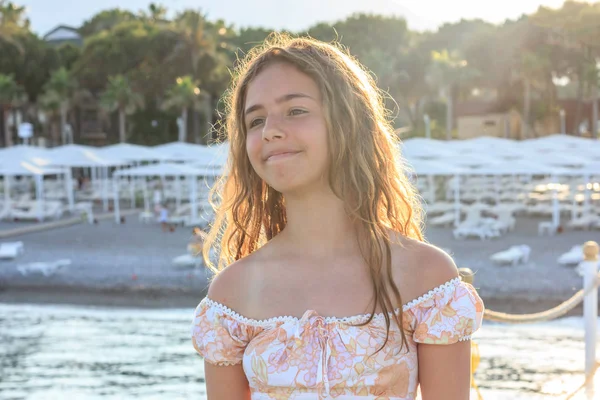 海の桟橋に沈む太陽の光の中で美しいティーンエイジャーの女の子 — ストック写真