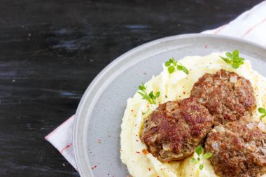 Taze fesleğen ile süslenmiş gri bir plaka üzerinde patates ve et topları püresi