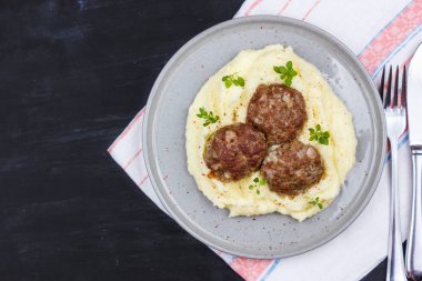Taze fesleğen ile süslenmiş gri bir plaka üzerinde patates ve et topları püresi