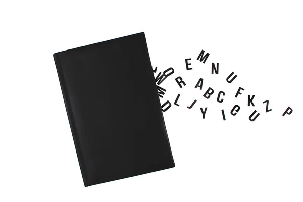 Black book with letters of the English alphabet. Letters fly out of a book