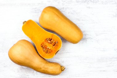 Beyaz bir masada balkabağı. Tatlı armut şekilli üç portakal kabağı