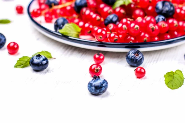 Fresh blueberries and red currants with mint leaves in a wooden bowl on burlap. Diet food, vegan berries — Stock Photo, Image