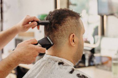 Berber berber dükkanında profesyonel makineyle şık saç kesimi yapıyor. Türk adam için saç kesimi.