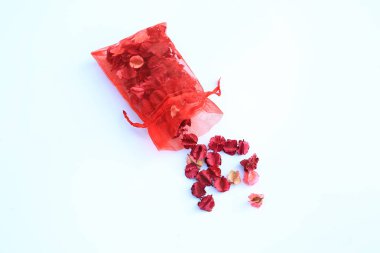 Beyaz arka plan üzerinde izole dökmek kuru pembe çiçekler kırmızı bez çanta.