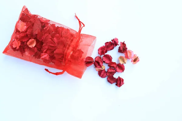 Worek Czerwony Tkaniny Pour Suche Różowe Kwiaty Białym Tle — Zdjęcie stockowe
