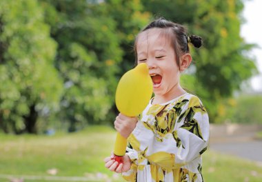 Sevimli küçük kız plastik hava pompası balon parkta güneşli bir günde kullanarak..