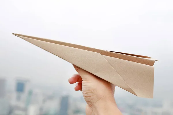 Brown aircraft rocket paper in hand fold to success on blur background of urban, Concept for business and travel plant.