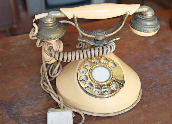 Vintage telephone. Retro beige rotary phone on wooden table