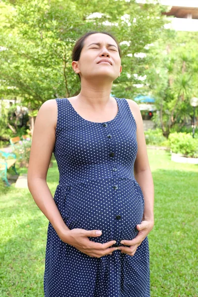 Pregnant woman with tummy ache in the garden.