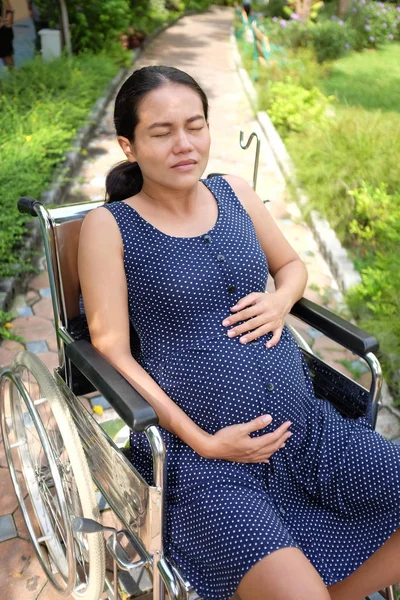 Pregnant woman with tummy ache on wheelchair