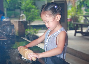 Hamur üzerinde ahşap oklava kullanarak çocuk.