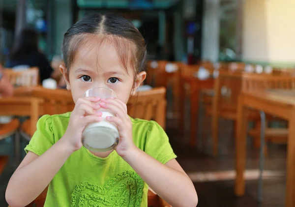 Little asian girl drinking milk in restaurant at the morning.