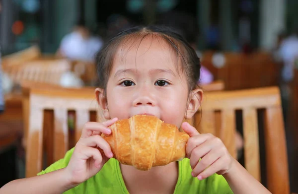 在餐馆吃羊角面包的可爱的小女孩 — 图库照片