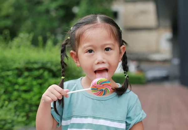 Fechar Menina Lambendo Pirulito Doce Jardim Com Câmera Olhando — Fotografia de Stock