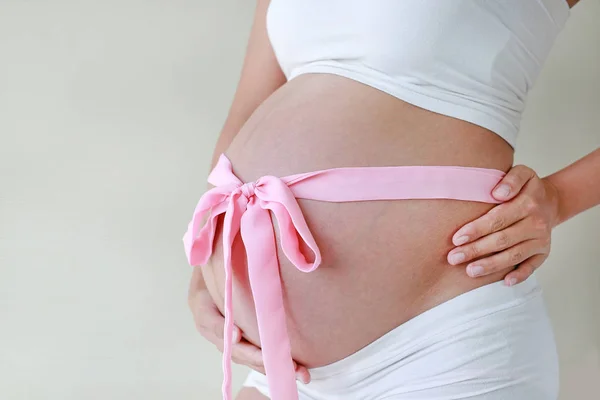 Close Van Buik Van Zwangere Vrouw Met Een Roze Lint — Stockfoto