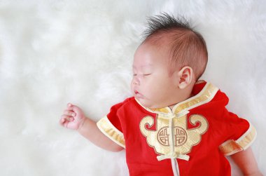 Beyaz kürk arka plan üzerinde geleneksel Çin yeni yılı festival sırasında yalan cheongsam erkek bebek bebek.