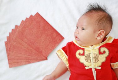 Yalan beyaz kürk arka plan üzerinde kırmızı zarflarla cheongsam erkek bebek bebek.