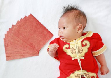 Yalan beyaz kürk arka plan üzerinde kırmızı zarflarla cheongsam erkek bebek bebek.