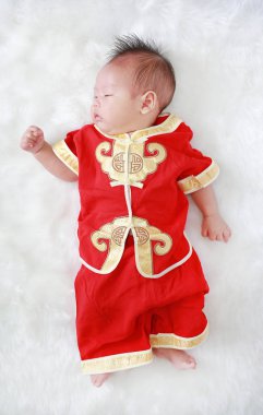 Beyaz kürk arka plan üzerinde geleneksel Çin yeni yılı festival sırasında yalan cheongsam erkek bebek bebek.