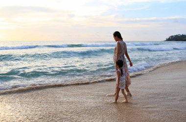 Hamile anne ve kızı gün batımında sahilde rahatlatıcı.