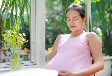 Kafede oturan ve karnı dokunmadan mutlu gebe.
