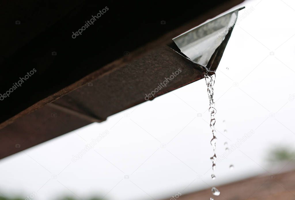 Rain flows down from a roof down