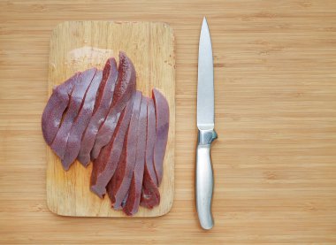 Ham taze dilimlenmiş domuz karaciğer ahşap tahta arka plan üzerinde keskin bıçak ile.