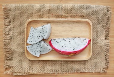 Taze dilimlenmiş dragon meyve ahşap tepsi ve çuval ahşap tahta arka plan.